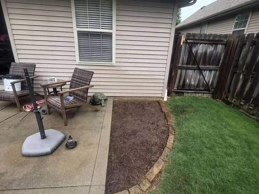 Stone border along a brick house beside a covered patio