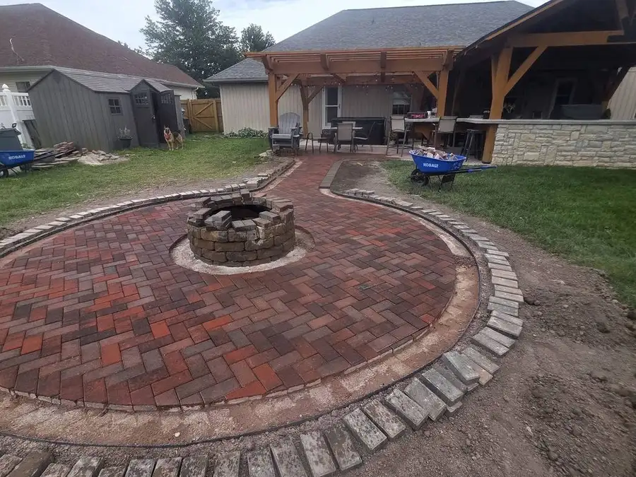 Close view of a soldier-course brick border being laid around a fire pit