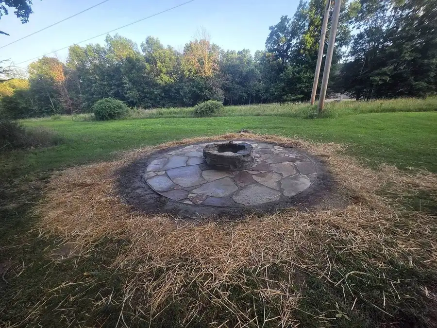 Wide view of a flagstone fire pit in a back lawn