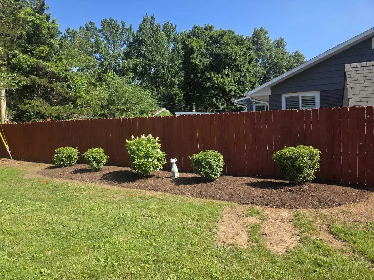 Fresh mulch in landscape beds along a residential fence
