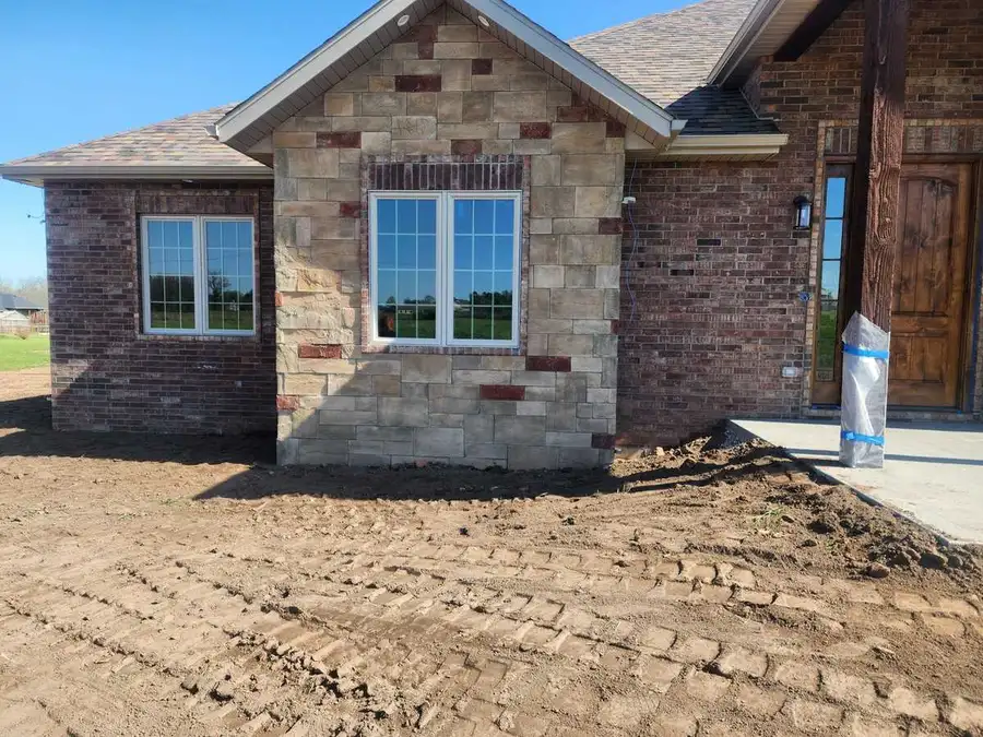 New-construction lot graded in front of a brick home