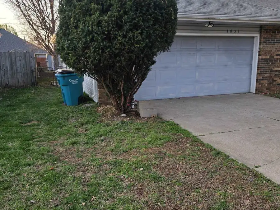 Overgrown shrub crowding a garage before a cleanup