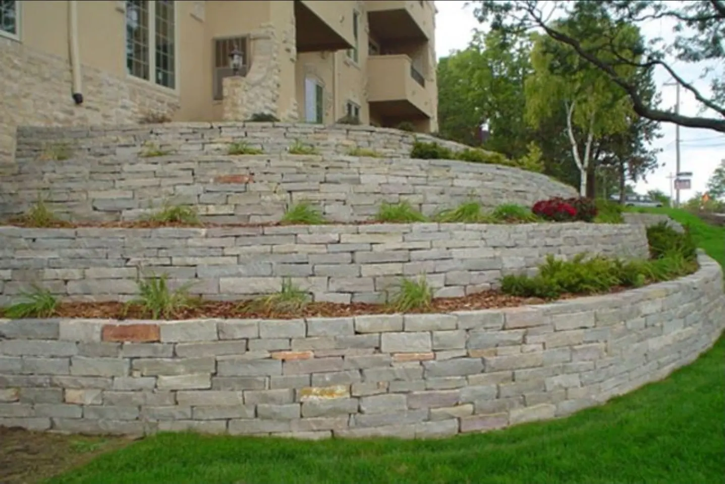 Tiered stone retaining wall with planted beds, built by Holy Grounds Landscaping