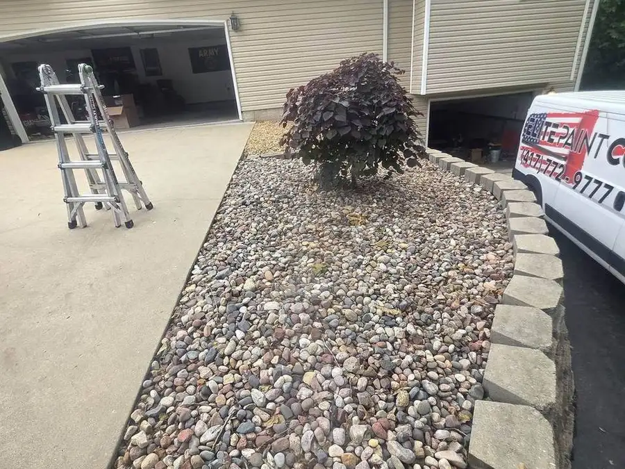 River rock bed with a shrub along a concrete driveway