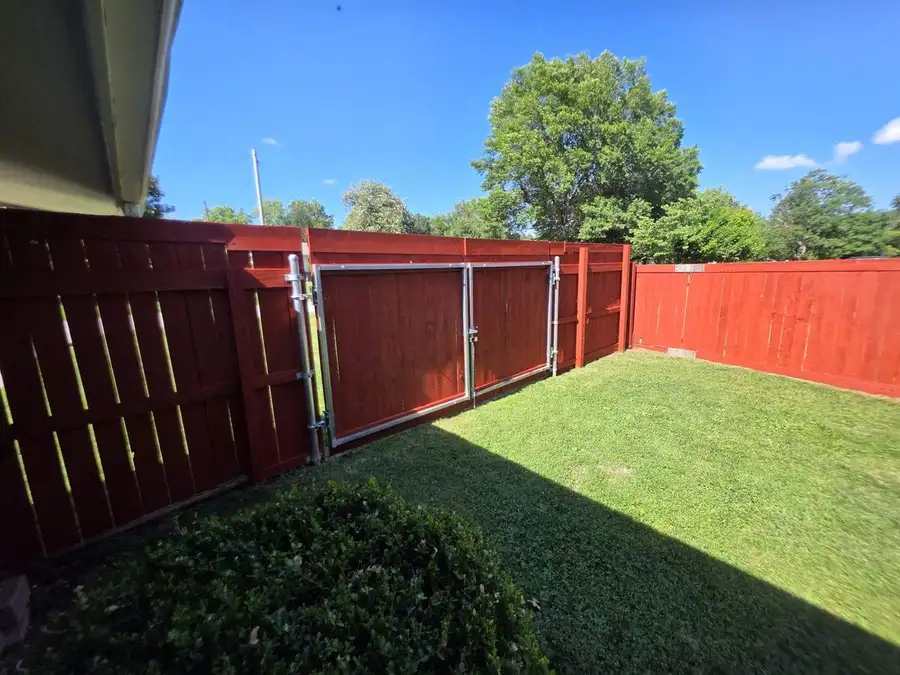 Stained privacy fence and gate along a lawn