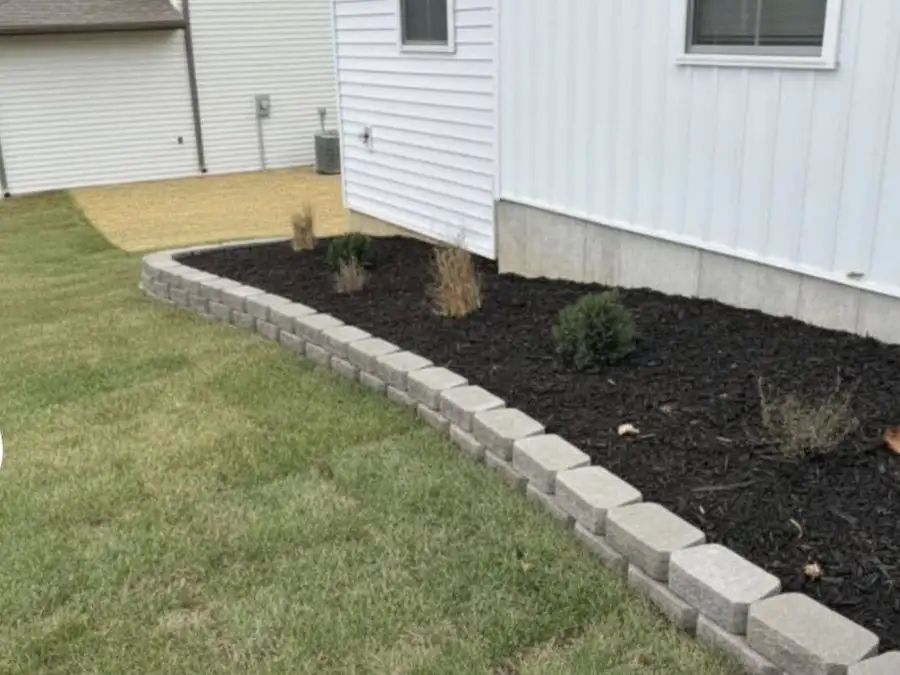Stone-bordered mulch bed along a white house